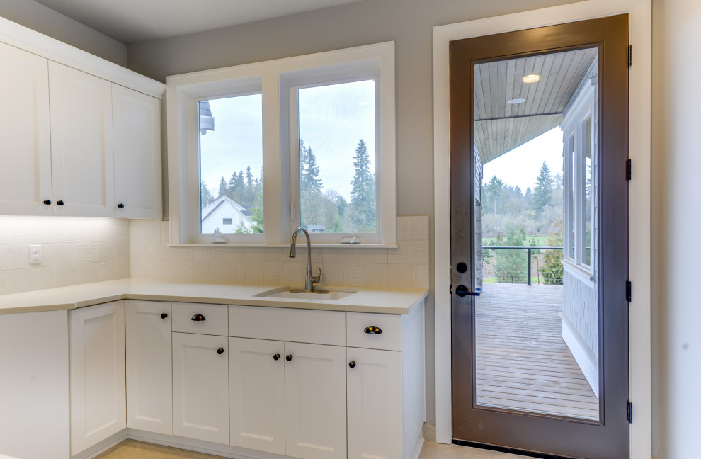 Example of a mid-sized transitional galley porcelain tile and gray floor dedicated laundry room design in Portland with an utility sink, shaker cabinets, white cabinets, quartz countertops, gray walls, a side-by-side washer/dryer and gray countertops