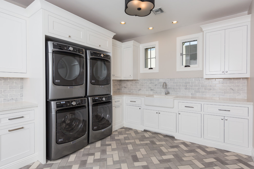 Foto på en mellanstor vintage vita l-formad tvättstuga enbart för tvätt, med en rustik diskho, luckor med profilerade fronter, vita skåp, bänkskiva i kvarts, vita väggar, tegelgolv, en tvättpelare och grått golv