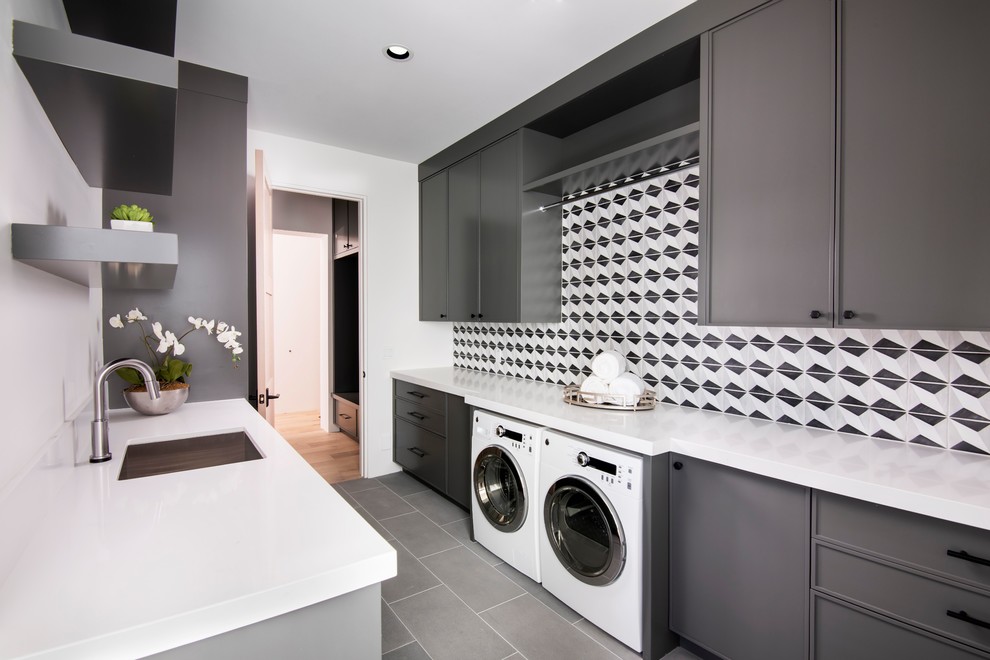 Foto di una lavanderia multiuso minimal con ante nere, pareti bianche, lavasciuga, pavimento grigio e top bianco