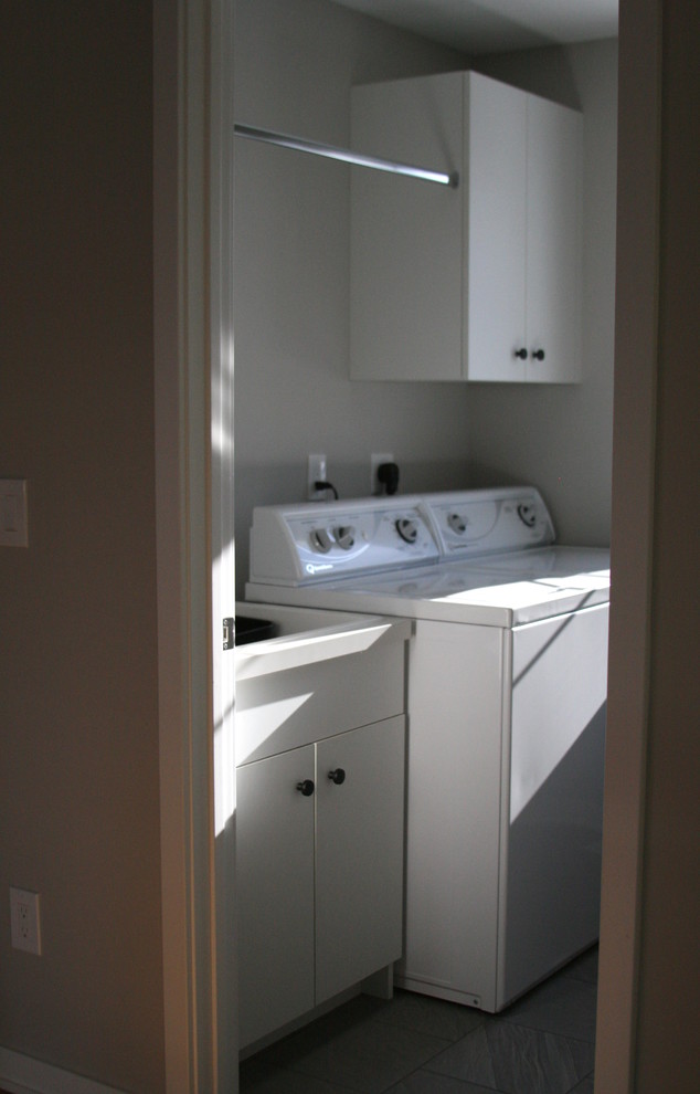 Inspiration for a small modern gray floor dedicated laundry room remodel in Minneapolis with flat-panel cabinets, white cabinets, gray walls and a side-by-side washer/dryer