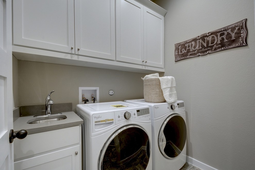 Exempel på en klassisk grå linjär grått tvättstuga enbart för tvätt, med en undermonterad diskho, skåp i shakerstil, grå skåp, grå väggar och en tvättmaskin och torktumlare bredvid varandra