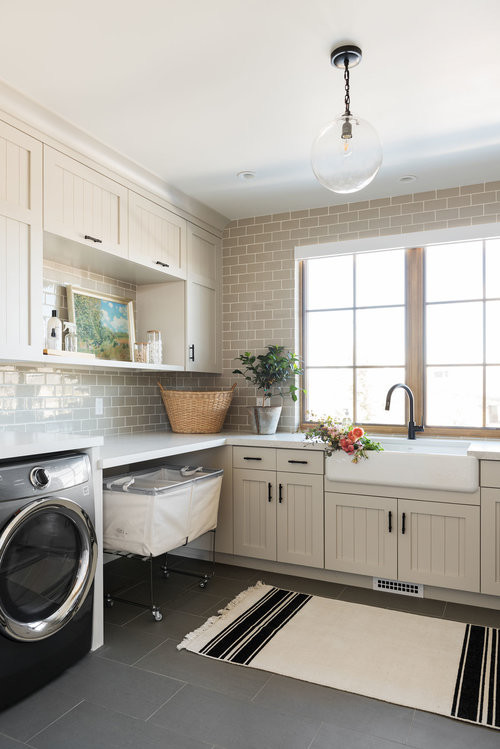 Laundry room - large transitional u-shaped ceramic tile and gray floor laundry room idea in Salt Lake City with a farmhouse sink and beige cabinets