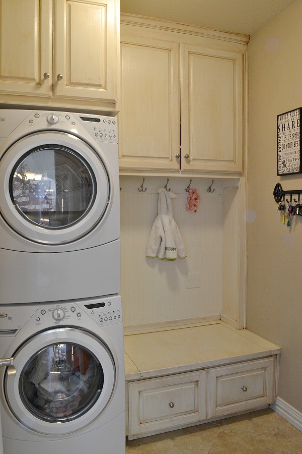 シアトルにあるお手頃価格の小さなトラディショナルスタイルのおしゃれな家事室 (I型、レイズドパネル扉のキャビネット、ベージュのキャビネット、ベージュの壁、セラミックタイルの床、上下配置の洗濯機・乾燥機、ベージュの床) の写真