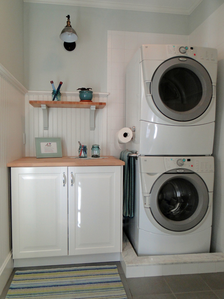 Einzeiliger Landhaus Hauswirtschaftsraum mit grauer Wandfarbe, Porzellan-Bodenfliesen und Waschmaschine und Trockner gestapelt in New York
