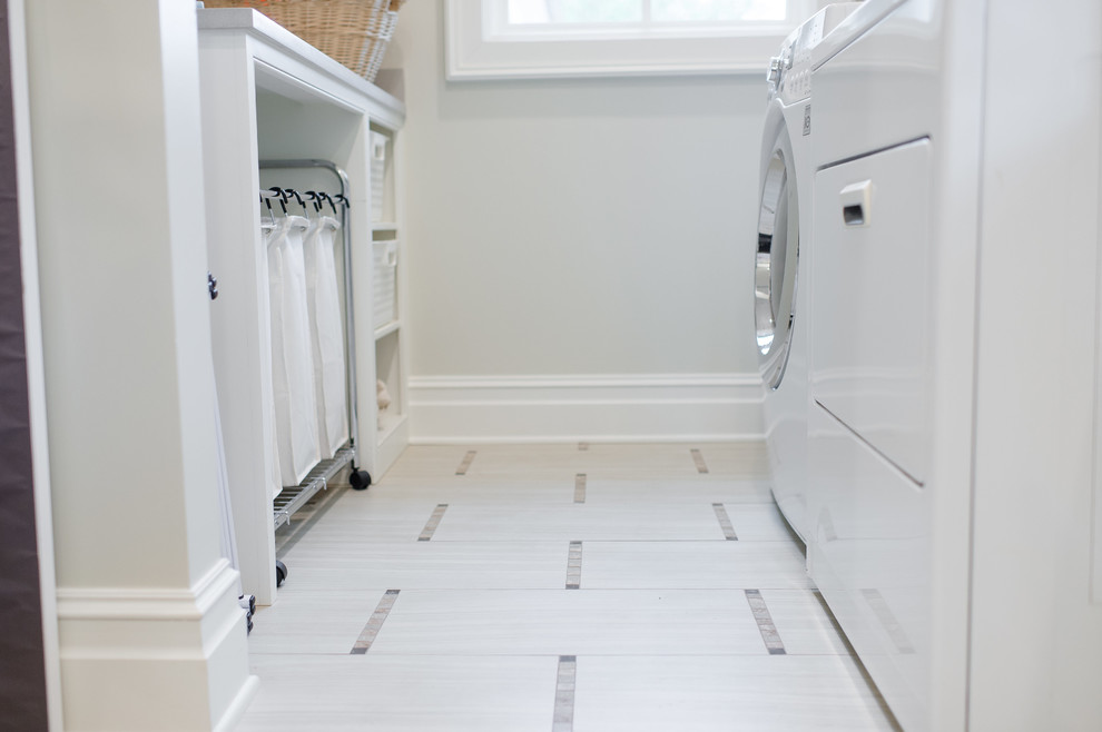 Inredning av en klassisk mellanstor parallell tvättstuga enbart för tvätt, med grå väggar, klinkergolv i porslin, en tvättmaskin och torktumlare bredvid varandra och vitt golv