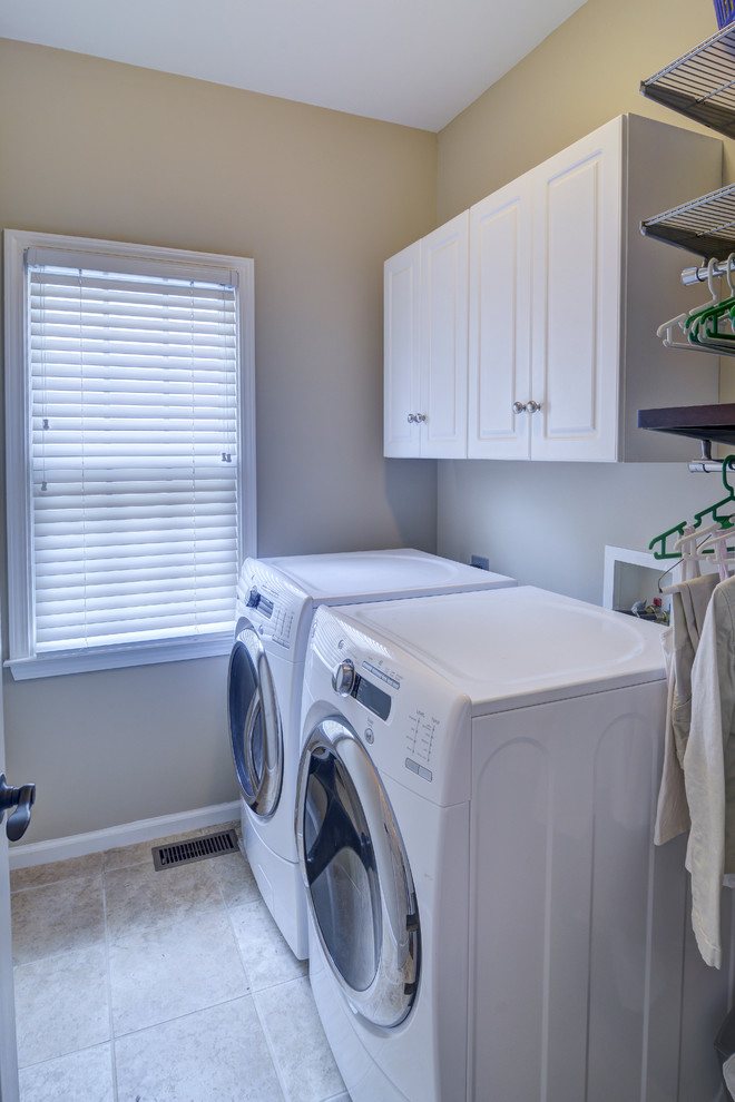 Esempio di una sala lavanderia classica di medie dimensioni con ante con bugna sagomata, ante bianche, pareti beige, pavimento in gres porcellanato e lavatrice e asciugatrice affiancate