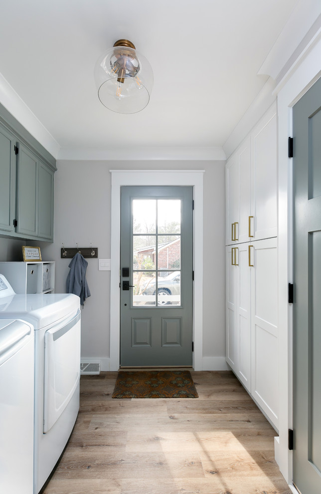 Foto di una sala lavanderia classica con ante in stile shaker, ante bianche, pareti grigie, lavatrice e asciugatrice affiancate, pavimento marrone e top bianco