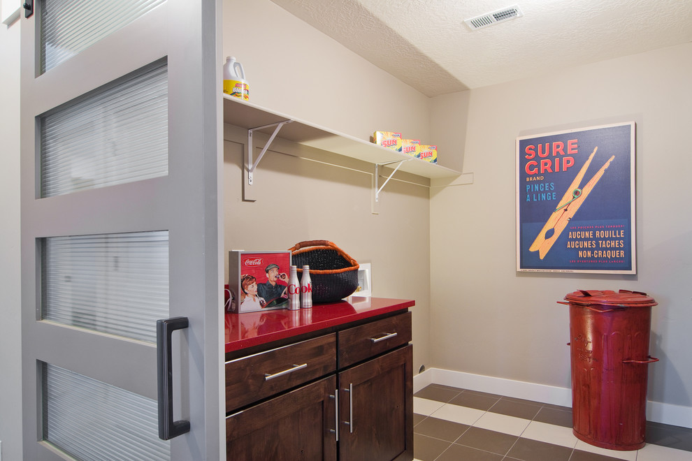 ソルトレイクシティにあるコンテンポラリースタイルのおしゃれな洗濯室 (中間色木目調キャビネット、ベージュの壁、セラミックタイルの床、I型、シェーカースタイル扉のキャビネット、赤いキッチンカウンター) の写真