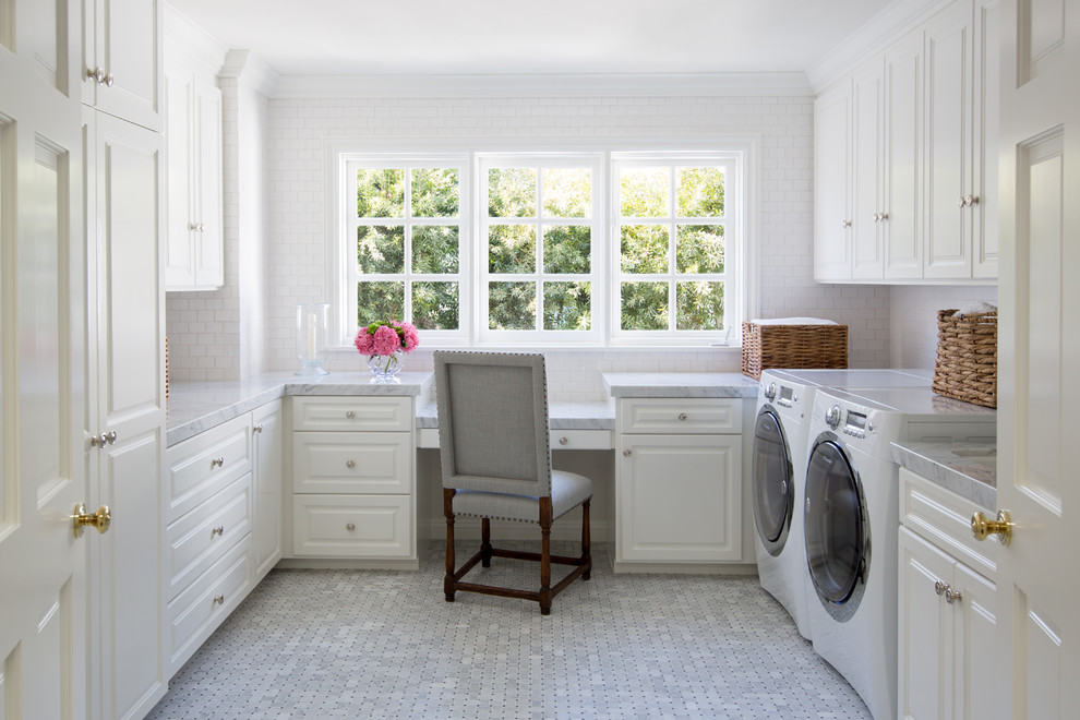 Mid-sized elegant u-shaped porcelain tile and gray floor utility room photo in Orange County with raised-panel cabinets, white cabinets, a side-by-side washer/dryer, marble countertops, white walls and gray countertops
