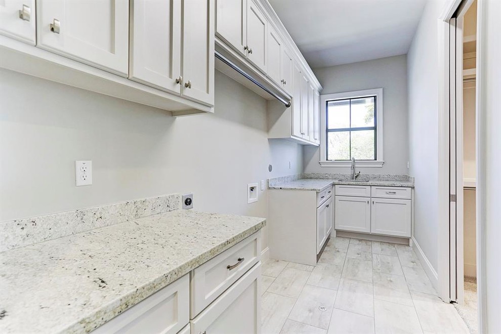 This is an example of a large contemporary l-shaped utility room in Houston with a built-in sink, shaker cabinets, white cabinets, granite worktops, grey walls, ceramic flooring, a side by side washer and dryer, white floors and white worktops.