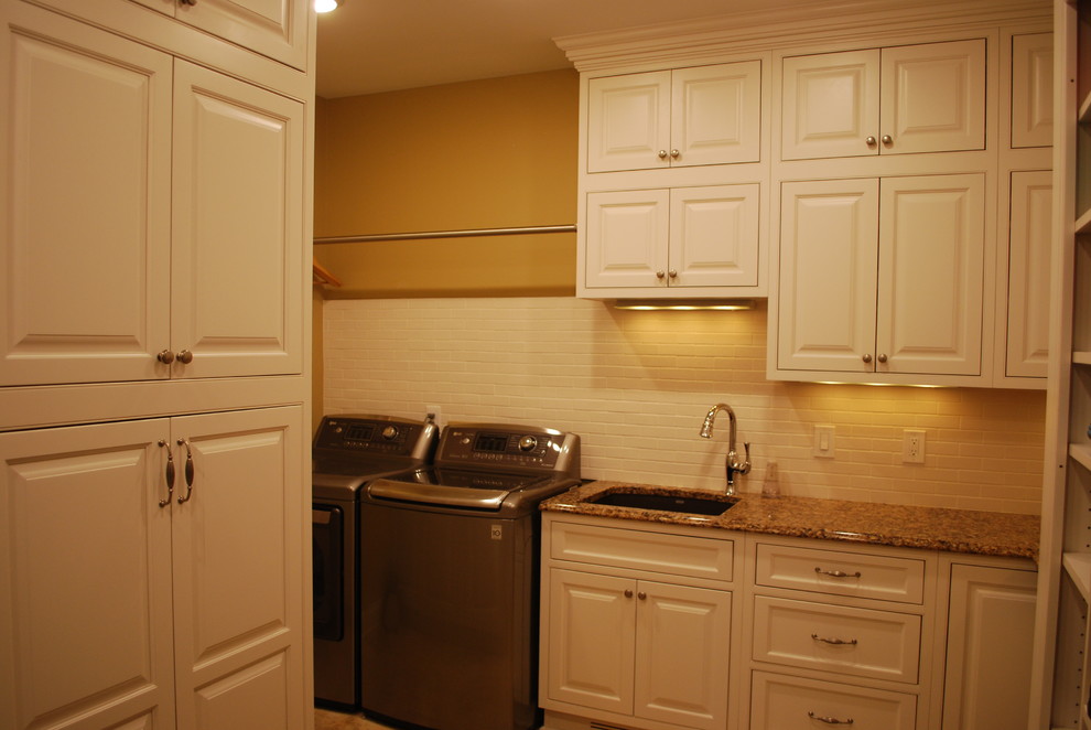 Klassisk inredning av ett stort u-format grovkök, med en undermonterad diskho, luckor med upphöjd panel, vita skåp, bänkskiva i kvarts, klinkergolv i porslin, en tvättmaskin och torktumlare bredvid varandra och bruna väggar