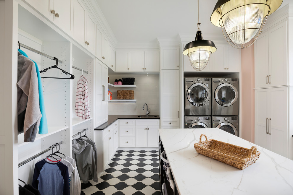 Photo of a traditional u-shaped utility room in Minneapolis with a submerged sink, shaker cabinets, white cabinets, pink walls, a stacked washer and dryer and white worktops.