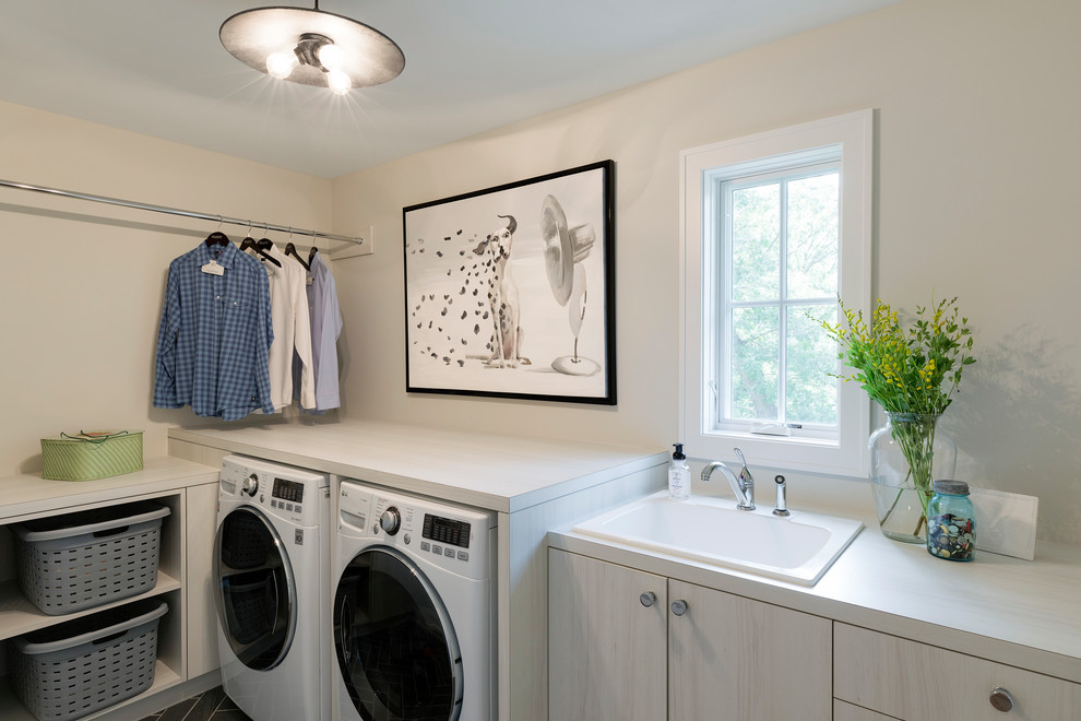 Modelo de cuarto de lavado tradicional renovado con fregadero encastrado, armarios con paneles lisos, paredes blancas y lavadora y secadora juntas