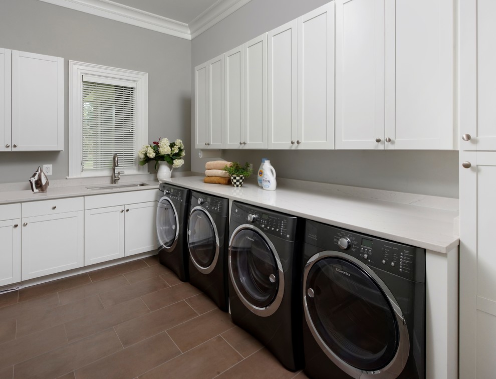 Large minimalist l-shaped porcelain tile and brown floor dedicated laundry room photo in DC Metro with an undermount sink, flat-panel cabinets, white cabinets, quartz countertops, gray walls and a side-by-side washer/dryer