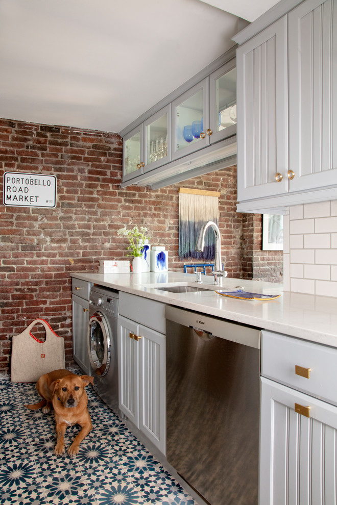 ボストンにあるトランジショナルスタイルのおしゃれな家事室 (アンダーカウンターシンク、グレーのキャビネット、マルチカラーの床、白いキッチンカウンター) の写真