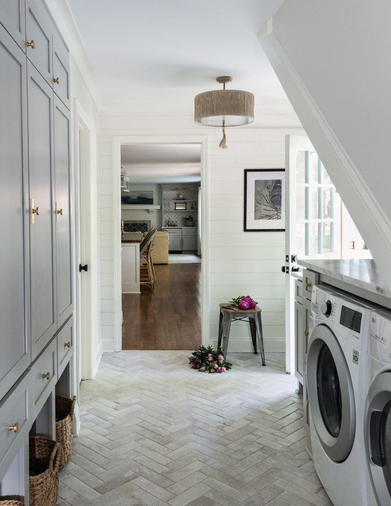 Exempel på ett klassiskt grå parallellt grått grovkök, med skåp i shakerstil, grå skåp, vita väggar, en tvättmaskin och torktumlare bredvid varandra och grått golv