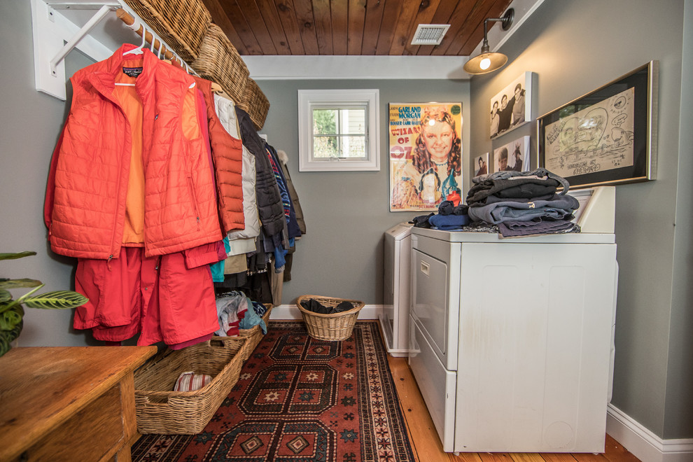 Photo of a medium sized rustic galley utility room in DC Metro with grey walls, medium hardwood flooring, a side by side washer and dryer and brown floors.