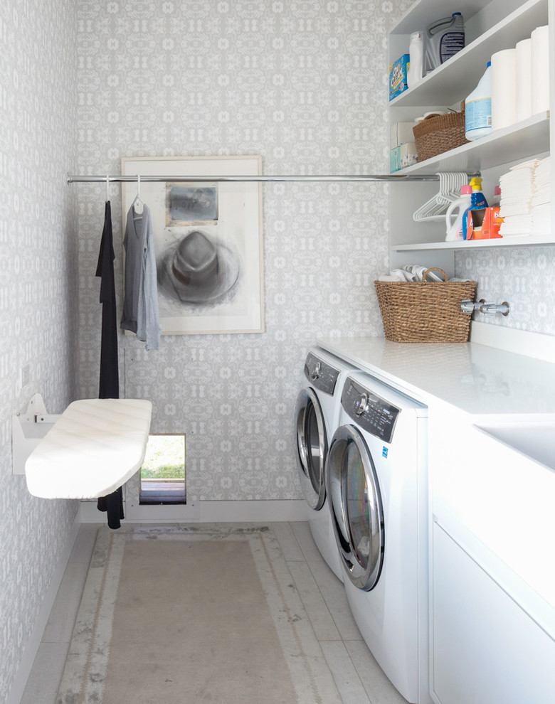 Modelo de cuarto de lavado lineal contemporáneo de tamaño medio con paredes blancas y lavadora y secadora juntas