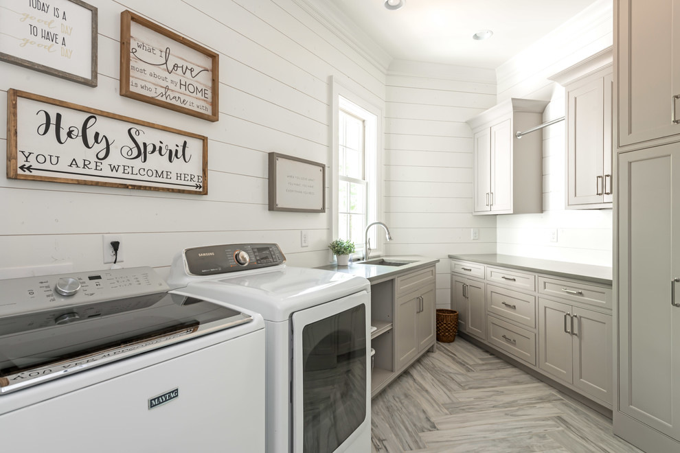 Foto di una sala lavanderia stile marinaro con lavatoio, ante con riquadro incassato, lavatrice e asciugatrice affiancate e pavimento grigio