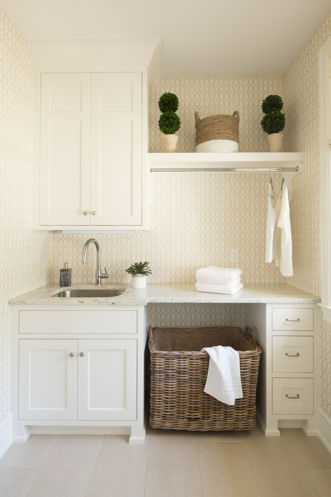 Esempio di una sala lavanderia costiera con lavello sottopiano, ante in stile shaker, ante bianche, pavimento beige e pareti beige