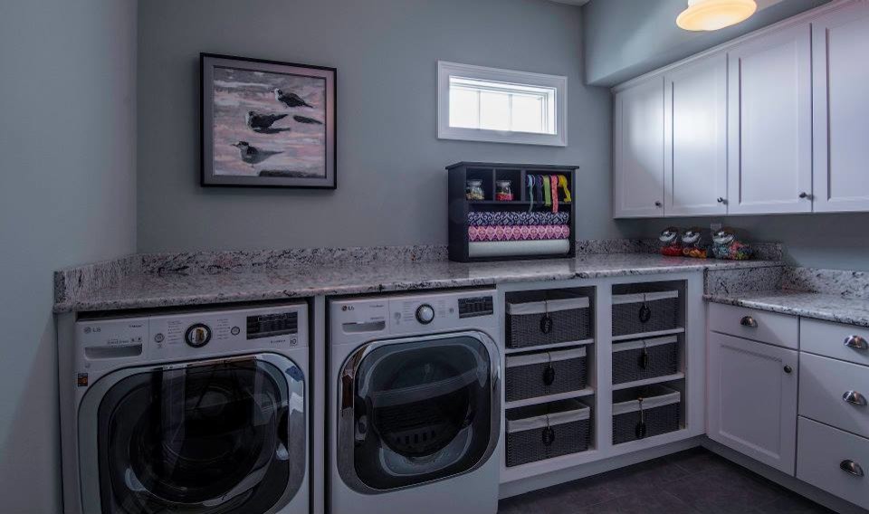 Idee per una sala lavanderia chic con ante in stile shaker, ante bianche, top in granito, pareti grigie, lavatrice e asciugatrice affiancate e top grigio