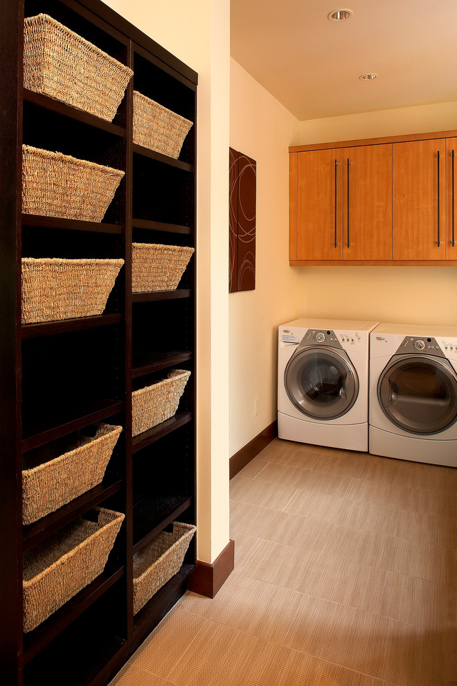 Idee per una lavanderia multiuso tradizionale di medie dimensioni con ante lisce, ante in legno chiaro, pareti gialle e lavatrice e asciugatrice affiancate