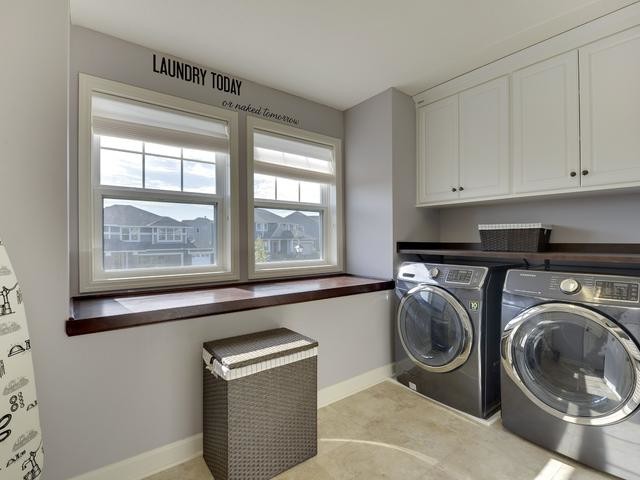 Immagine di una sala lavanderia stile americano di medie dimensioni con ante bianche, pareti grigie e lavatrice e asciugatrice affiancate