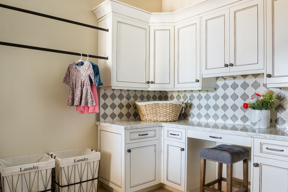 Bild på en medelhavsstil l-formad tvättstuga enbart för tvätt, med luckor med infälld panel, marmorbänkskiva, beige väggar och vita skåp
