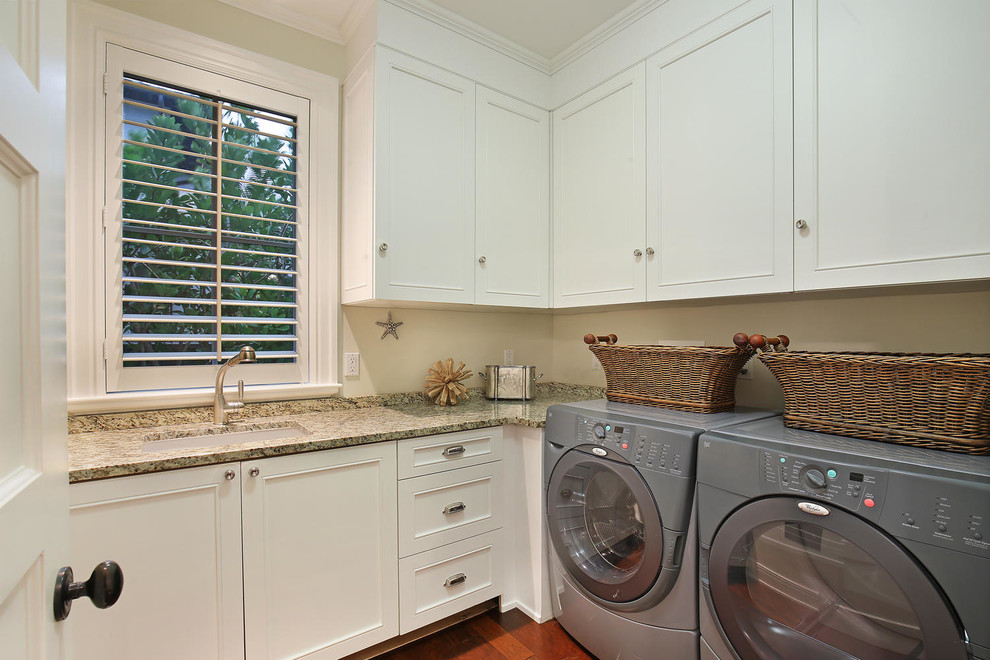 Large world-inspired l-shaped separated utility room in Tampa with a single-bowl sink, shaker cabinets, white cabinets, granite worktops, beige walls, medium hardwood flooring and a side by side washer and dryer.