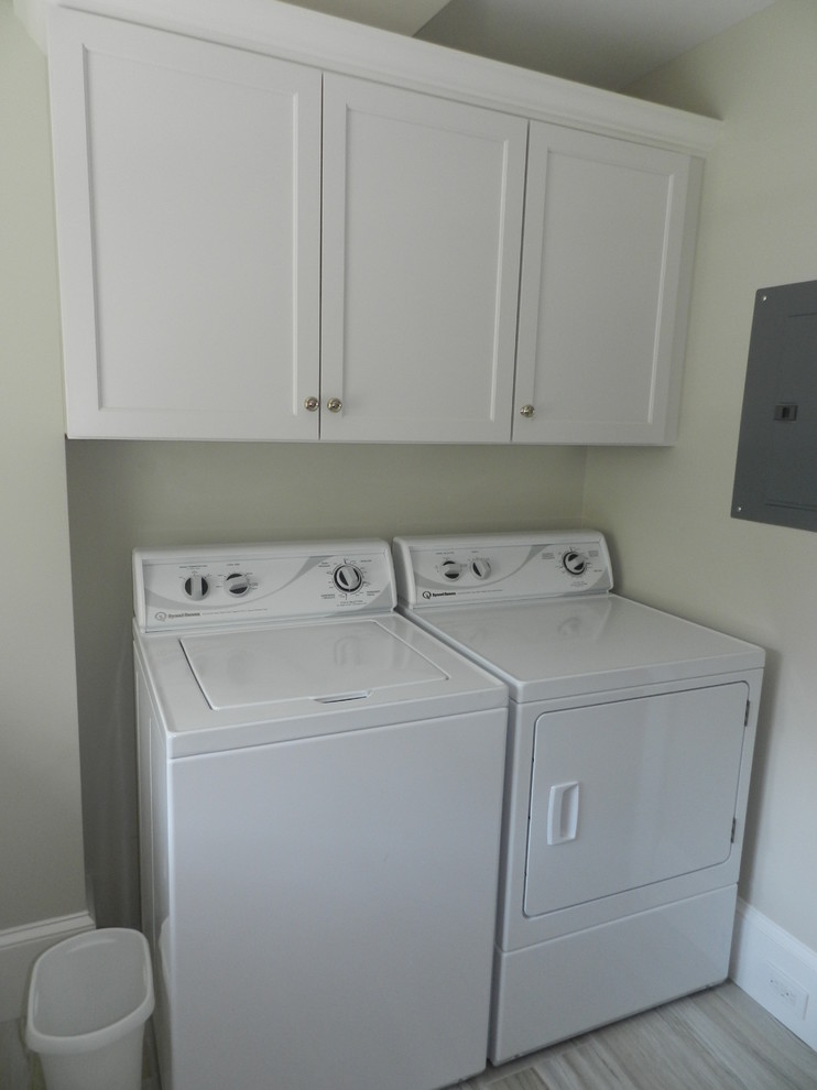 Foto på en mellanstor maritim tvättstuga enbart för tvätt, med en undermonterad diskho, vita skåp, bänkskiva i kvarts, grå väggar, klinkergolv i keramik och en tvättmaskin och torktumlare bredvid varandra