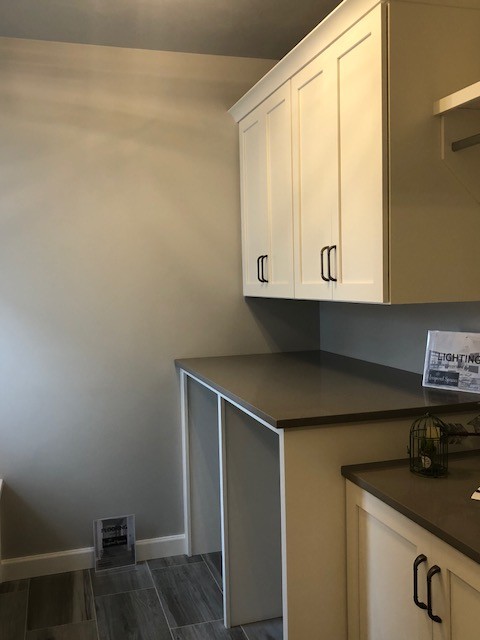 Inspiration for a classic galley utility room in Milwaukee with flat-panel cabinets, beige cabinets, granite worktops, grey walls, ceramic flooring, a side by side washer and dryer and grey floors.