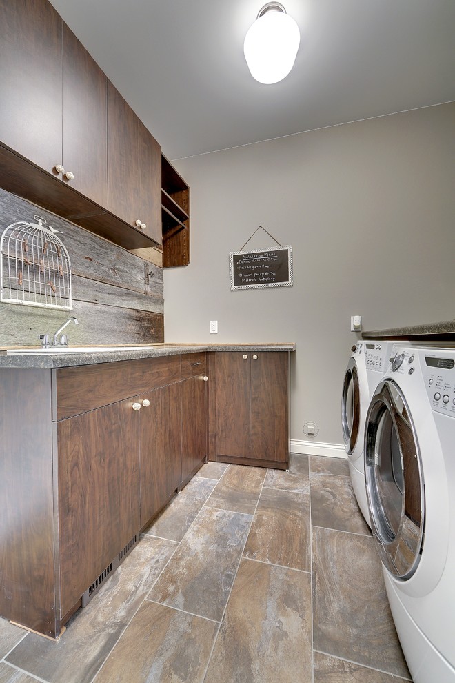 Example of a mid-sized transitional galley ceramic tile dedicated laundry room design in Minneapolis with a single-bowl sink, flat-panel cabinets, dark wood cabinets, gray walls, a side-by-side washer/dryer and laminate countertops