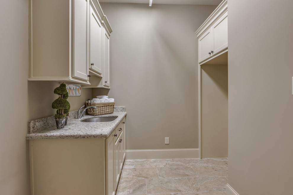 Large mediterranean single-wall separated utility room in Houston with a submerged sink, recessed-panel cabinets, white cabinets, granite worktops, beige walls, ceramic flooring, a side by side washer and dryer and beige floors.