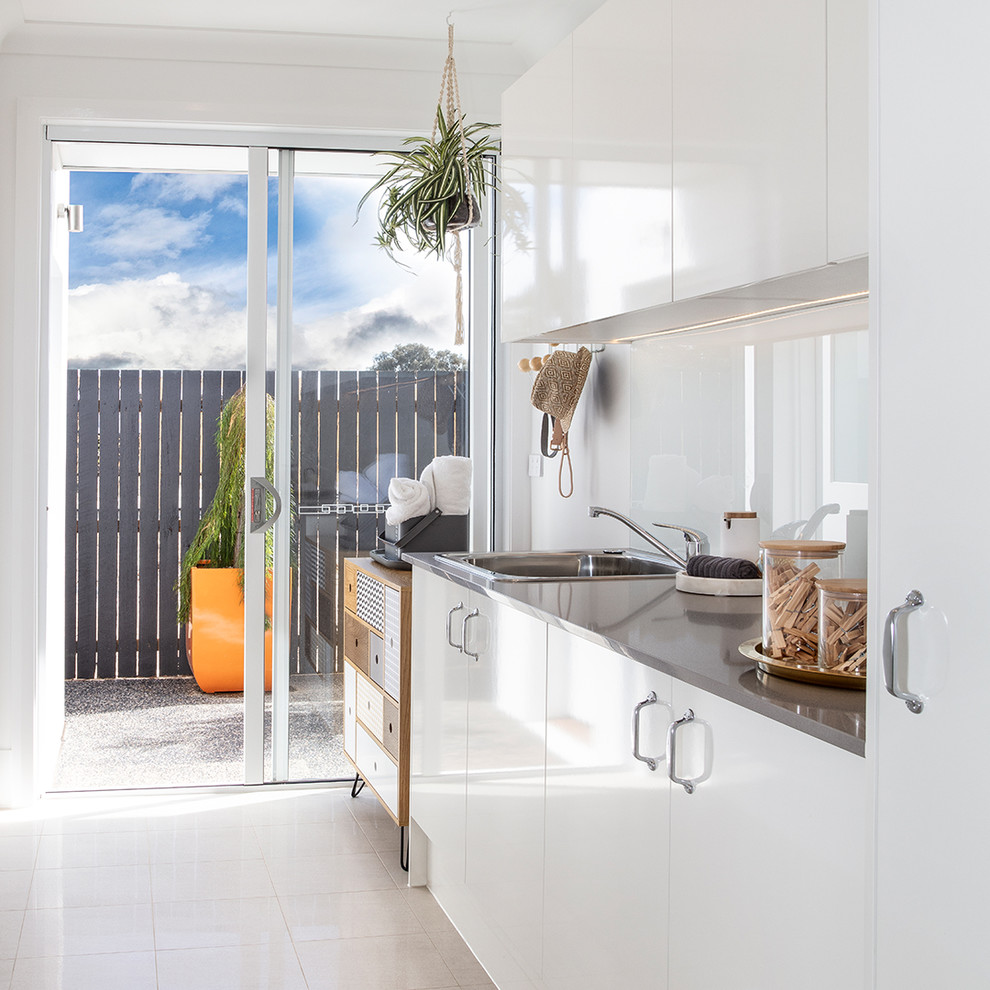 Retro galley separated utility room in Canberra - Queanbeyan with a built-in sink, white cabinets, granite worktops, white walls, ceramic flooring, grey worktops, flat-panel cabinets and white floors.