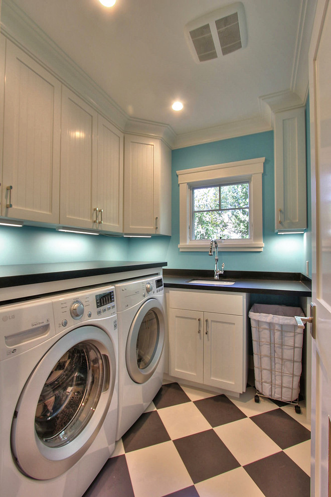 Idéer för mellanstora vintage l-formade tvättstugor enbart för tvätt, med en undermonterad diskho, skåp i shakerstil, vita skåp, laminatbänkskiva, blå väggar och en tvättmaskin och torktumlare bredvid varandra