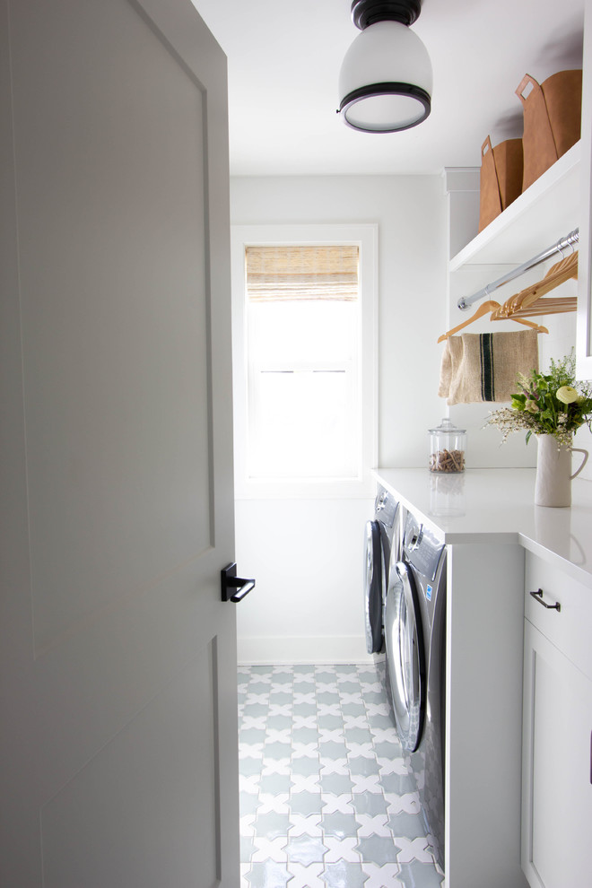 Idéer för mellanstora vintage linjära vitt tvättstugor enbart för tvätt, med luckor med upphöjd panel, vita skåp, bänkskiva i kvarts, vita väggar, klinkergolv i keramik, en tvättmaskin och torktumlare bredvid varandra och flerfärgat golv