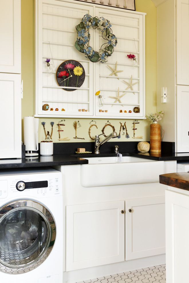 Imagen de lavadero campestre con fregadero sobremueble, armarios estilo shaker, puertas de armario blancas, paredes amarillas y encimeras negras