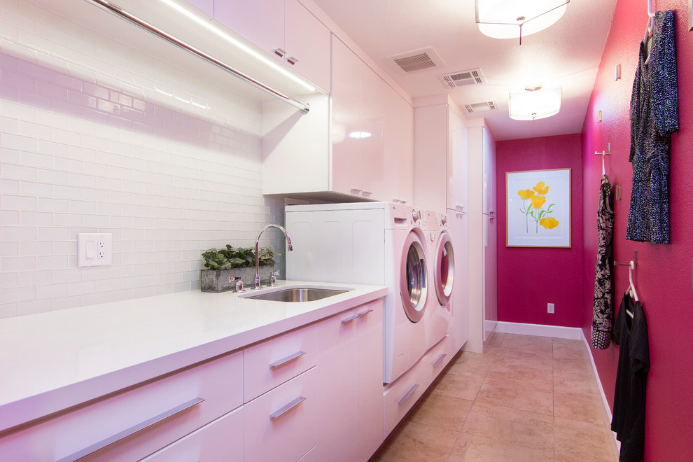 Modern inredning av ett stort parallellt grovkök, med en undermonterad diskho, släta luckor, vita skåp, bänkskiva i kvarts, rosa väggar, klinkergolv i porslin, en tvättmaskin och torktumlare bredvid varandra och beiget golv