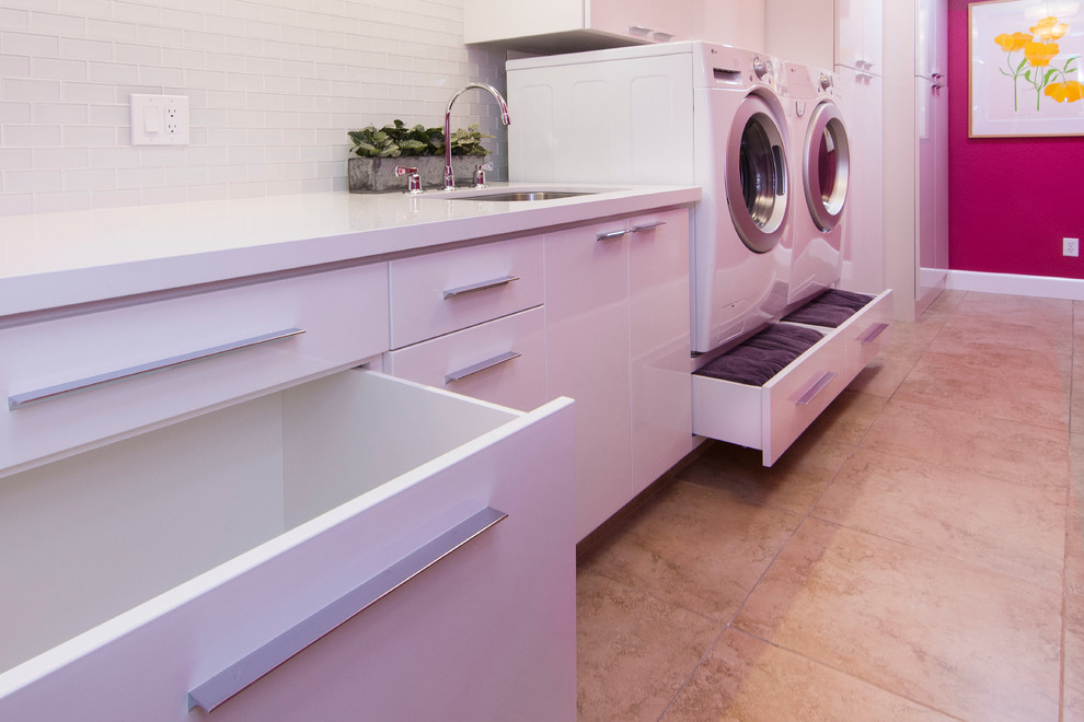 Exempel på ett stort modernt parallellt grovkök, med en undermonterad diskho, släta luckor, vita skåp, bänkskiva i kvarts, rosa väggar, klinkergolv i porslin och en tvättmaskin och torktumlare bredvid varandra