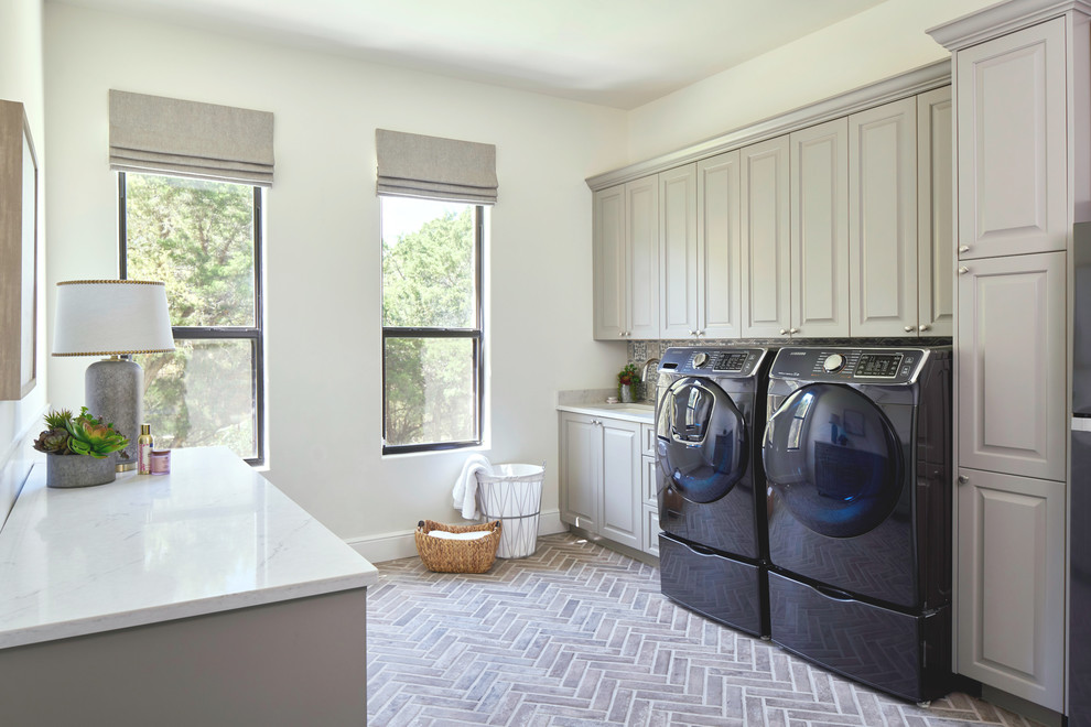 Foto di un'ampia sala lavanderia tradizionale con lavello sottopiano, ante con bugna sagomata, ante grigie, top in quarzo composito, lavatrice e asciugatrice affiancate e top bianco