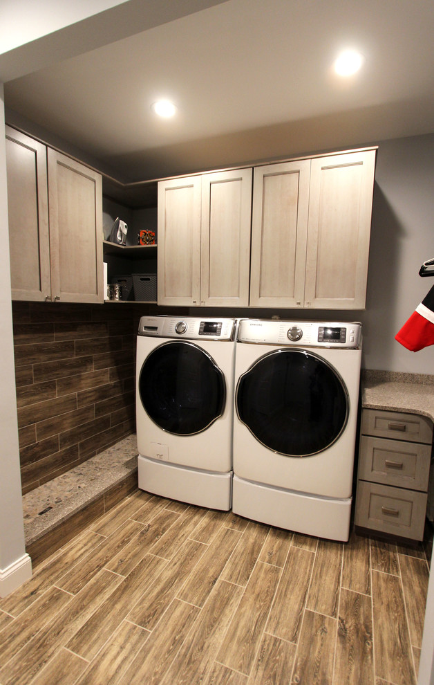 Exempel på ett mellanstort klassiskt parallellt grovkök, med släta luckor, grå skåp, bänkskiva i kvarts, grå väggar, laminatgolv, en tvättmaskin och torktumlare bredvid varandra och brunt golv