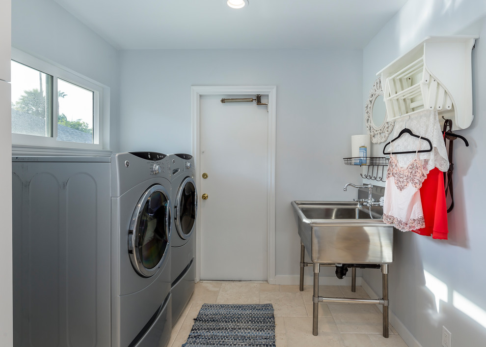 Idéer för en liten klassisk u-formad tvättstuga enbart för tvätt, med en allbänk, vita väggar, en tvättmaskin och torktumlare bredvid varandra, vita skåp, travertin golv och luckor med infälld panel