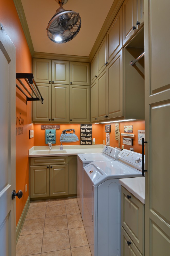 Inredning av en klassisk mellanstor l-formad tvättstuga enbart för tvätt, med en integrerad diskho, luckor med upphöjd panel, gröna skåp, bänkskiva i koppar, orange väggar, klinkergolv i keramik och en tvättmaskin och torktumlare bredvid varandra