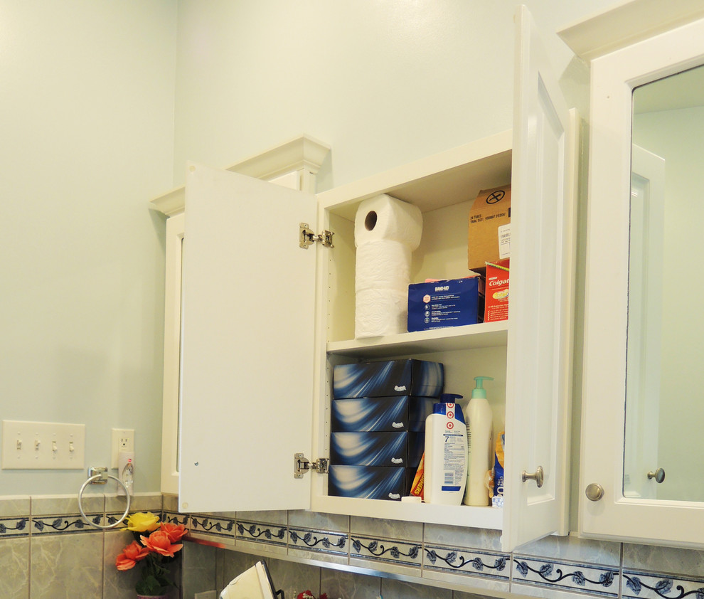 Foto di una lavanderia multiuso chic di medie dimensioni con ante lisce, ante bianche, top in laminato, pareti bianche, pavimento in vinile e lavatrice e asciugatrice a colonna