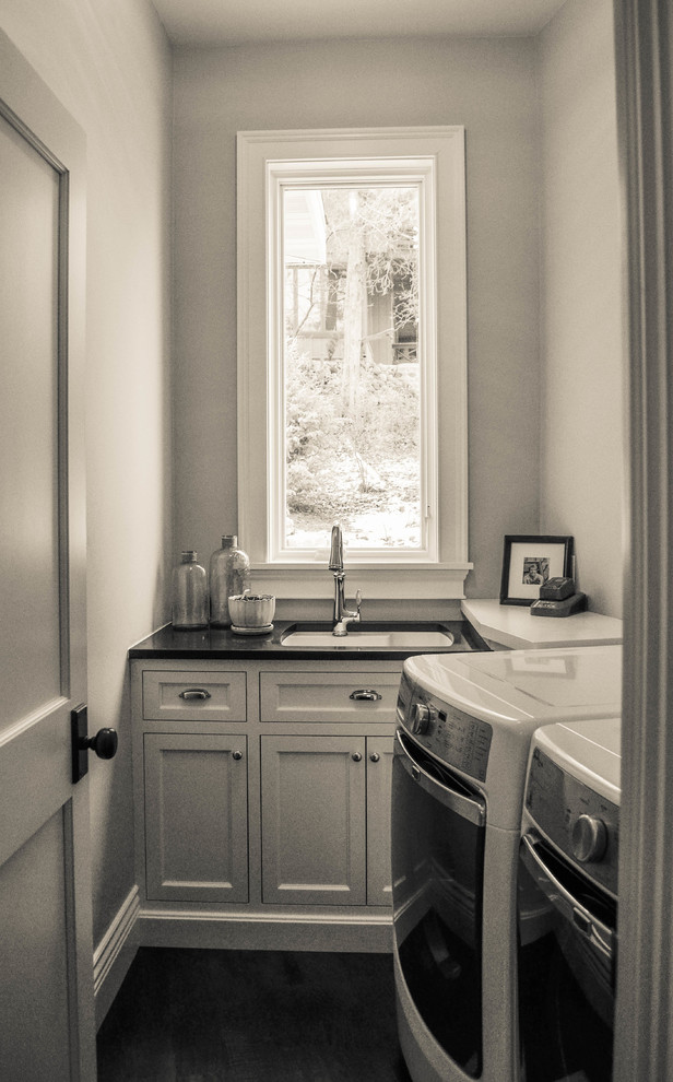 Immagine di una sala lavanderia stile marinaro di medie dimensioni con lavello sottopiano, ante lisce, ante bianche, top in granito, pareti grigie, parquet scuro e lavatrice e asciugatrice affiancate
