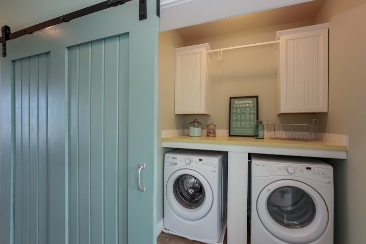 Ispirazione per una piccola sala lavanderia stile marinaro con ante con riquadro incassato, ante bianche, top in superficie solida e lavatrice e asciugatrice affiancate