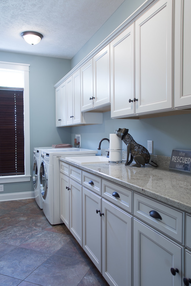 Photo of a large classic single-wall separated utility room in Cleveland with a built-in sink, recessed-panel cabinets, white cabinets, granite worktops, blue walls, porcelain flooring, a side by side washer and dryer, multi-coloured floors and multicoloured worktops.