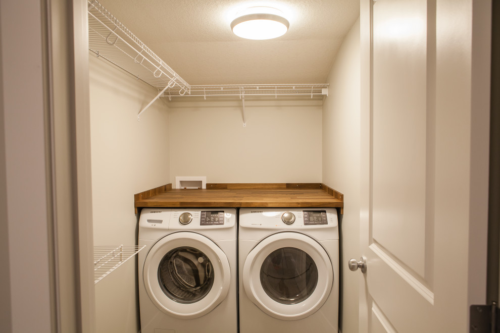 Esempio di un piccolo ripostiglio-lavanderia design con top in legno, pareti grigie, lavatrice e asciugatrice affiancate e top marrone
