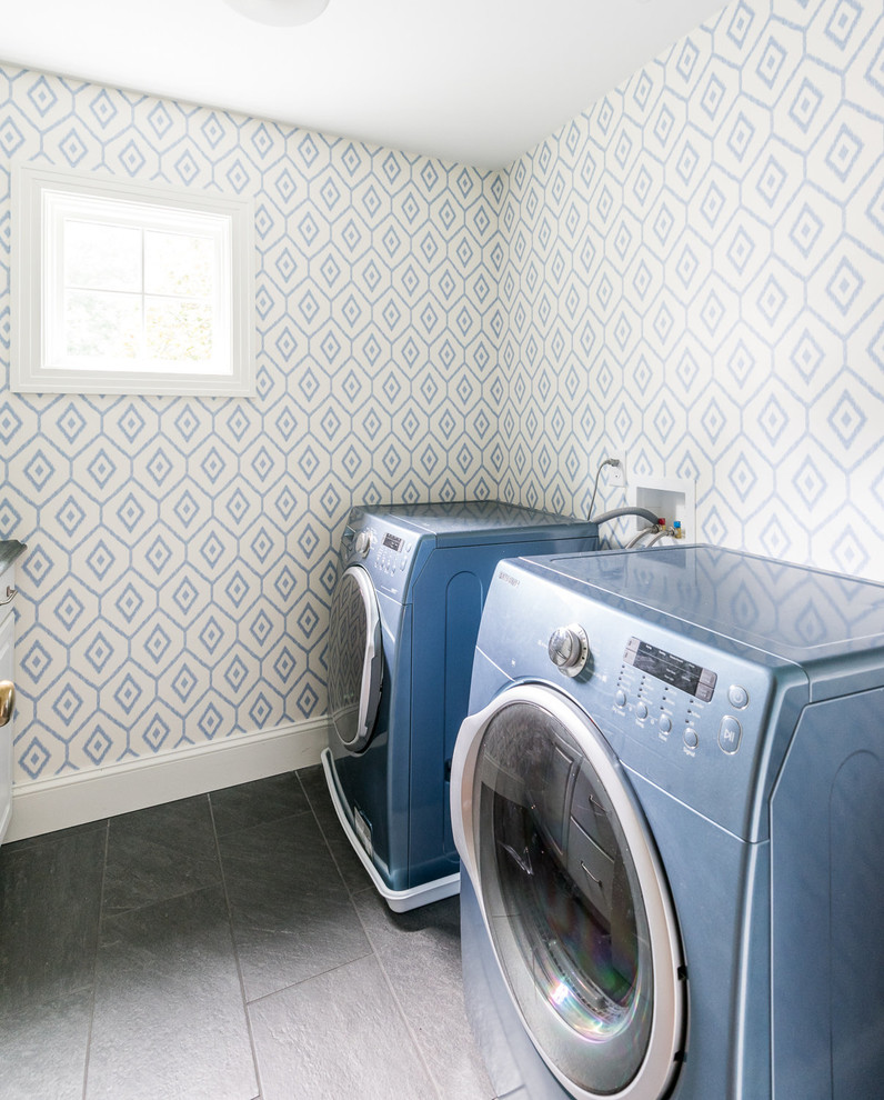 Inredning av en tvättstuga enbart för tvätt, med blå väggar, skiffergolv och en tvättmaskin och torktumlare bredvid varandra