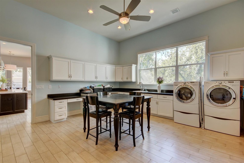 Huge transitional l-shaped light wood floor utility room photo in Phoenix with a drop-in sink, shaker cabinets, white cabinets, solid surface countertops, blue walls and a side-by-side washer/dryer